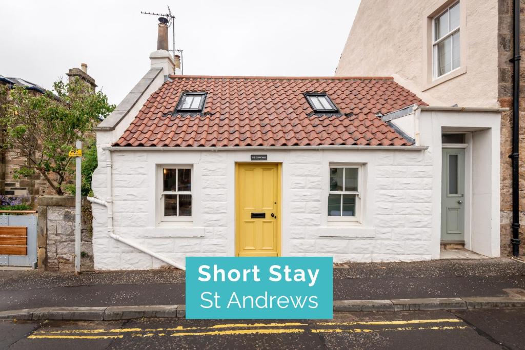 una casa blanca con una puerta amarilla en una calle en The Cupboard , Cosy Weavers Cottage , Wood Burner, en Elie