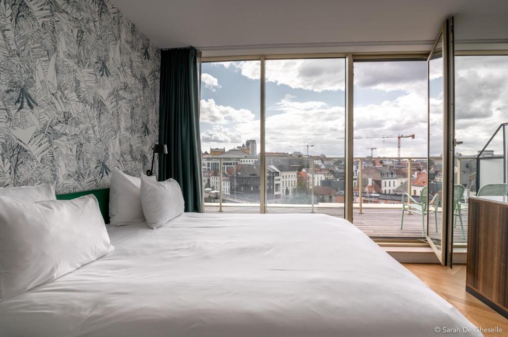 een slaapkamer met een groot wit bed en een groot raam bij Yalo Urban Boutique Hotel Gent in Gent