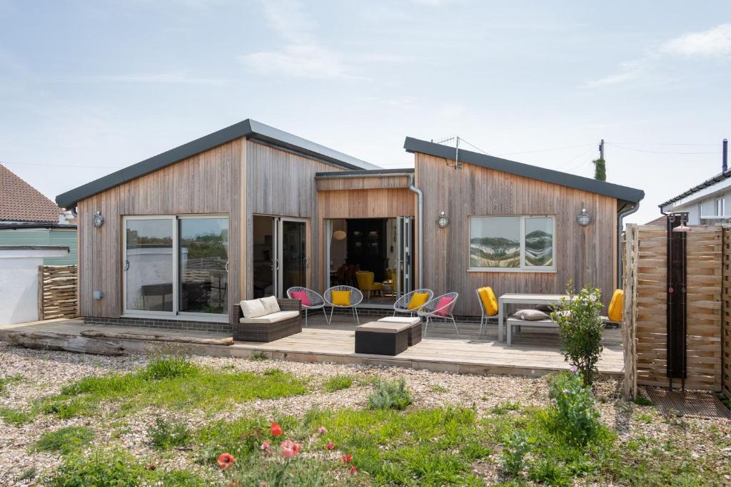 a wooden house with a deck and chairs at Sea Breezes in Pagham