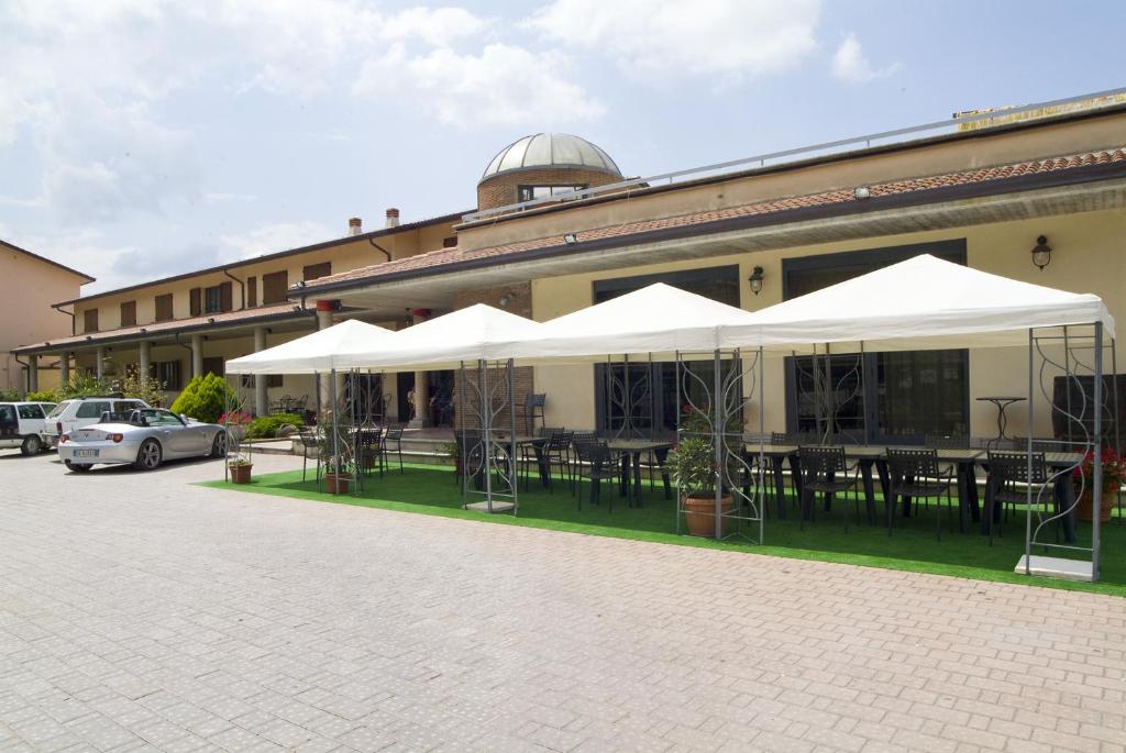 a building with tables and white umbrellas in front of it at Dominus Hotel in Sigillo