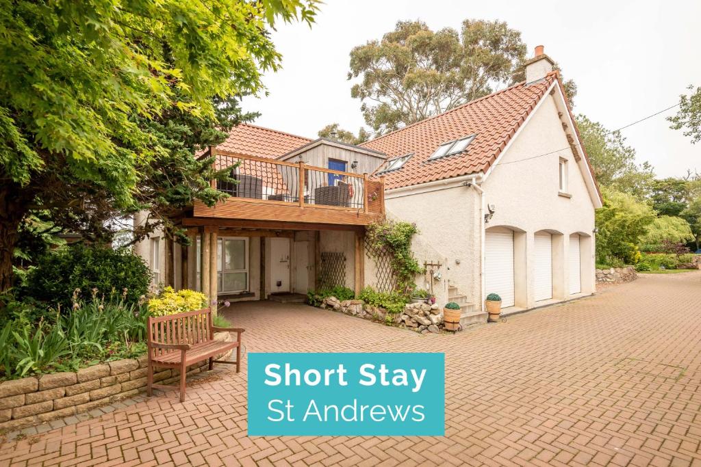 a house with a balcony and a bench on a brick driveway at Muir Park Cottage , 5 Mins to St Andrews , Parking in St Andrews