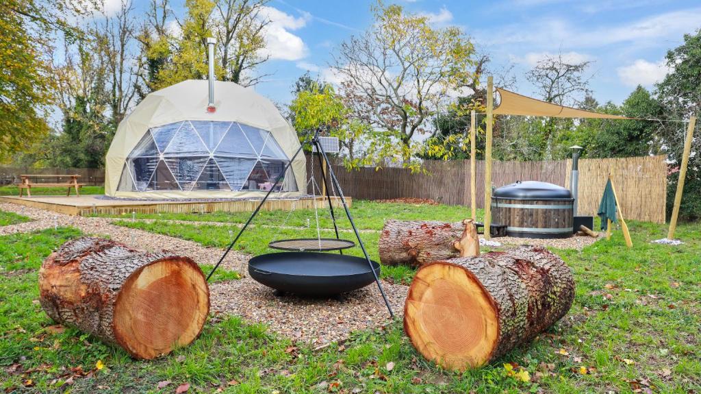 eine Gruppe von Baumstämmen und ein Zelt auf einem Hof in der Unterkunft Luxury Dome with Private Wood-Fired Hot Tub in Oxford