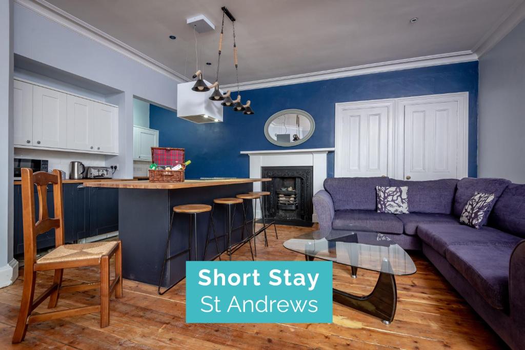 ein Wohnzimmer mit einem lila Sofa und einer Küche in der Unterkunft Market Street Apartment Sleeps 6 in St Andrews