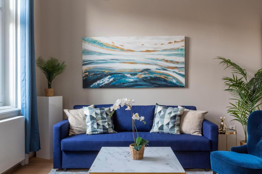 un sofá azul en una sala de estar con una pintura en Luxury Elizabeth Residence next to the New York Café, en Budapest