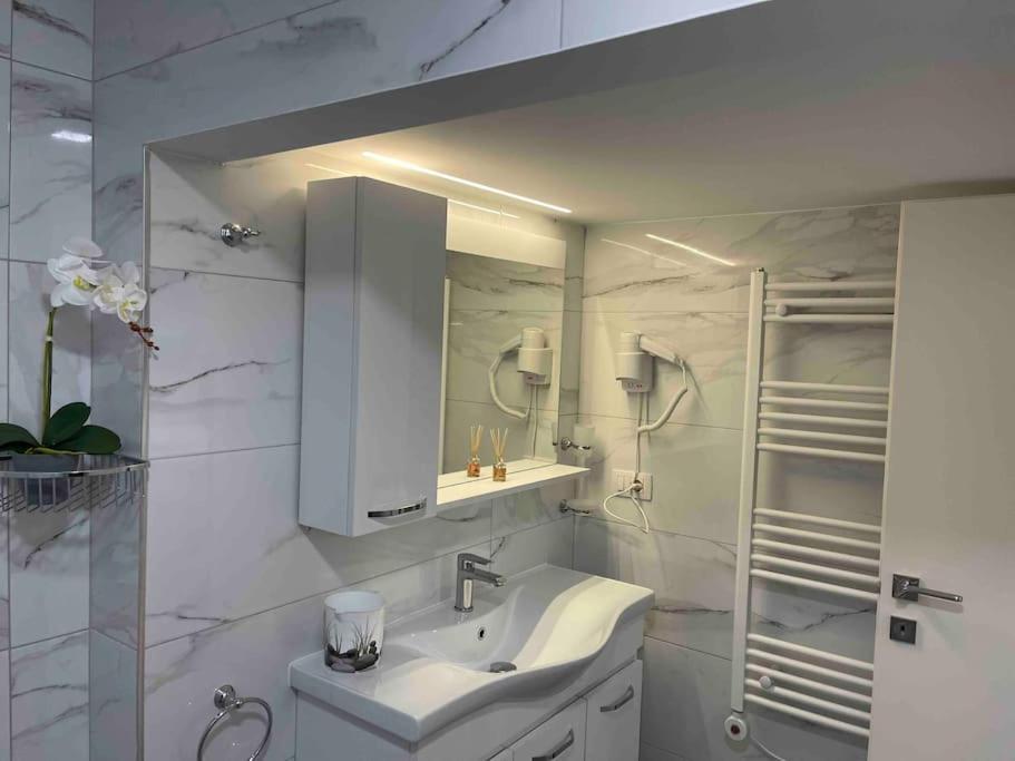 W białej łazience znajduje się umywalka i lustro. w obiekcie Lovely apartment in Pogradec city with a lake view w mieście Pogradec