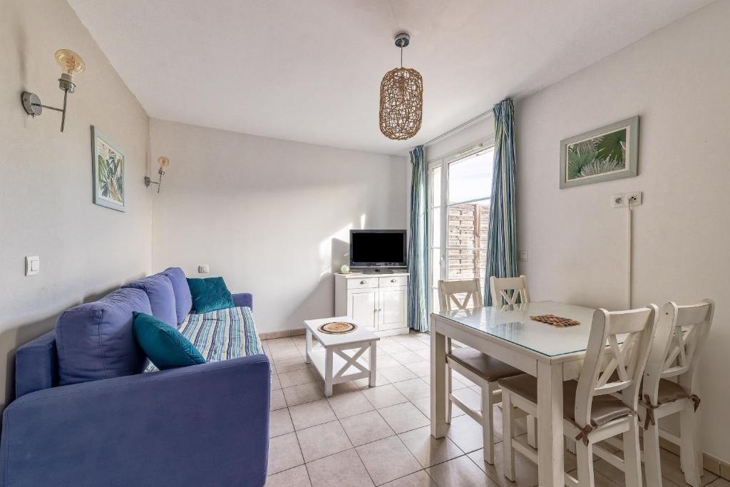 een woonkamer met een blauwe bank en een tafel bij L'Arbois - T2 avec piscine entre Aix et Marseille in Cabriès