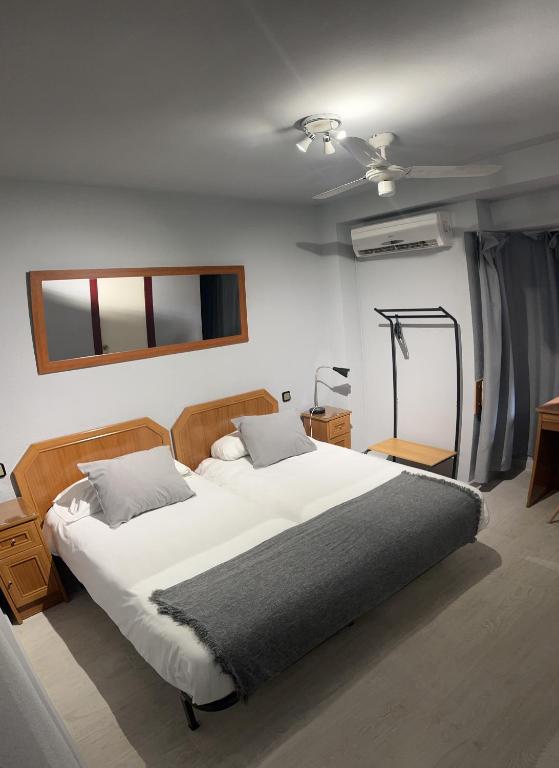 a bedroom with a large white bed and a window at Hostal Arenal in Zaragoza