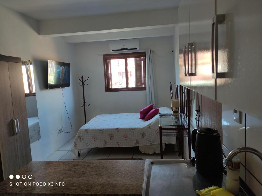 um pequeno quarto com uma cama e uma janela em Kitnet da Fô em Pelotas