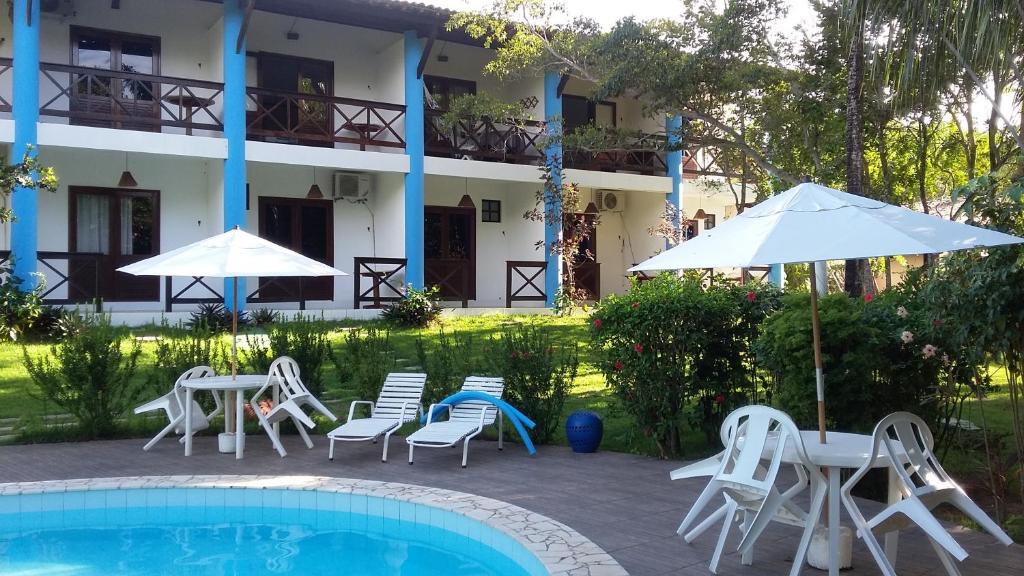 ein Hotel mit einem Pool, Stühlen, Tischen und Sonnenschirmen in der Unterkunft Imbassai Flat in Imbassai