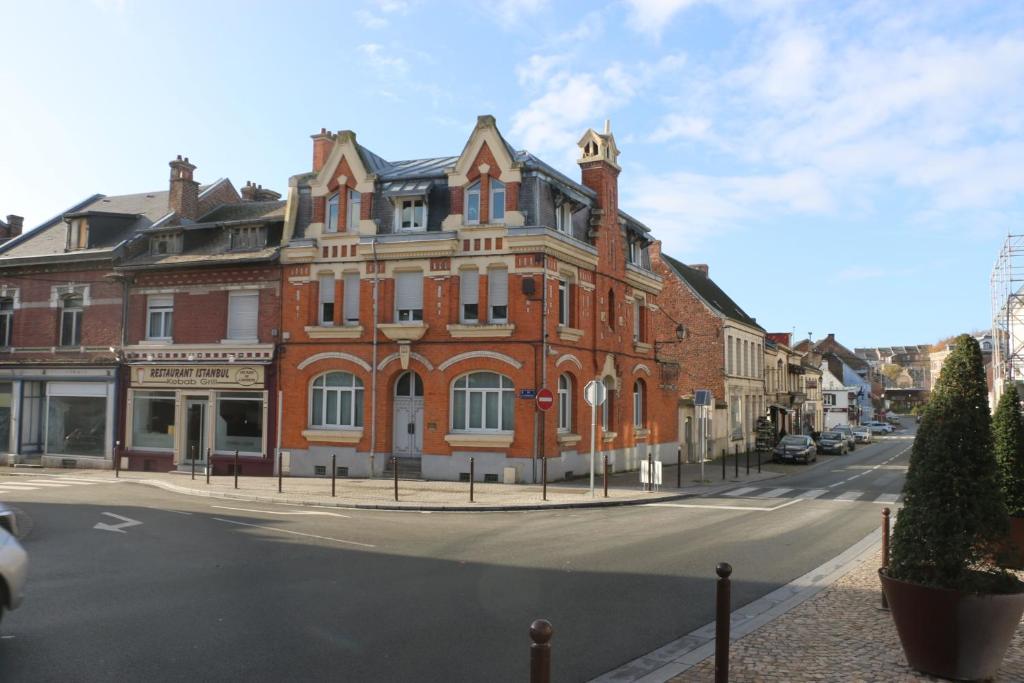 duży budynek z czerwonej cegły przy ulicy miejskiej w obiekcie Face à Matisse w mieście Le Cateau