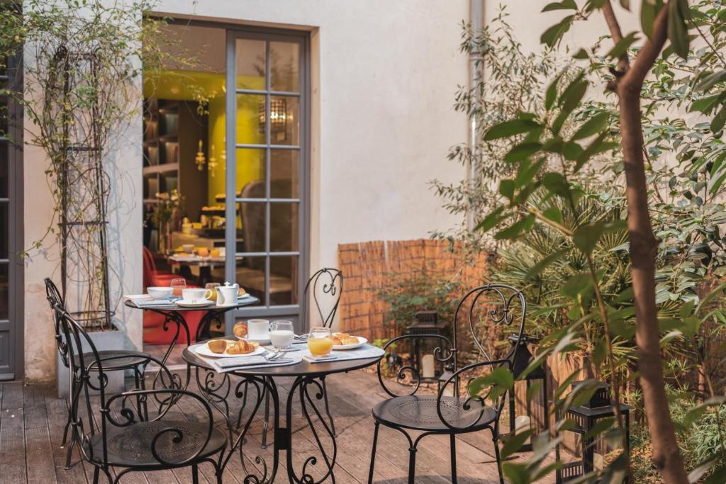 een patio met 2 tafels en stoelen met eten erop bij Hotel Le petit Paris in Parijs