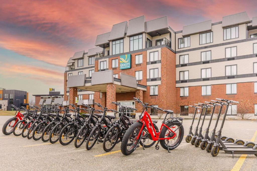 a row of bikes parked in a parking lot in front of a building at Quality Inn & Suites in Victoriaville
