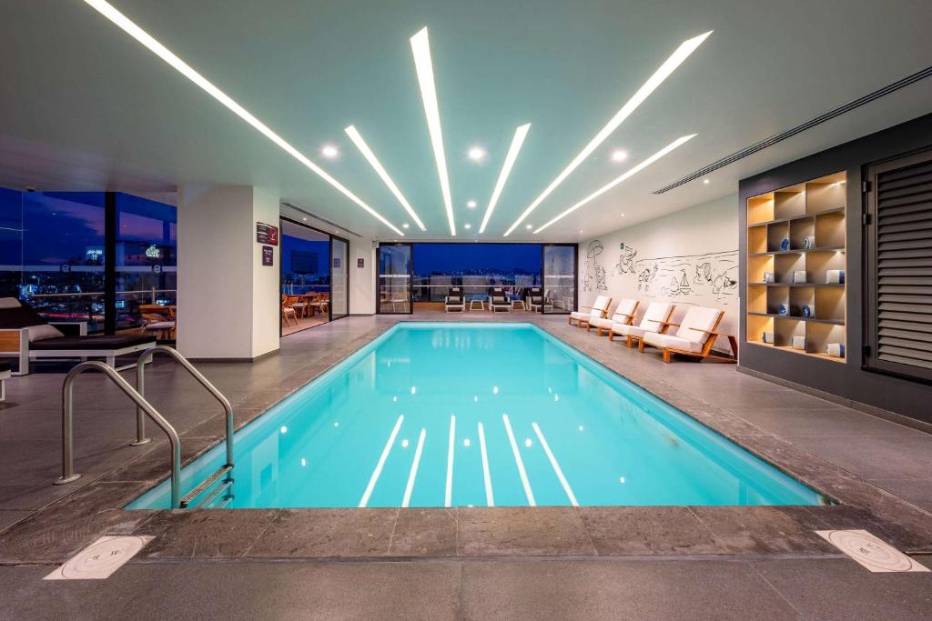 a swimming pool in a building with a restaurant at Ramada Encore by Wyndham Guadalajara Aeropuerto in Guadalajara