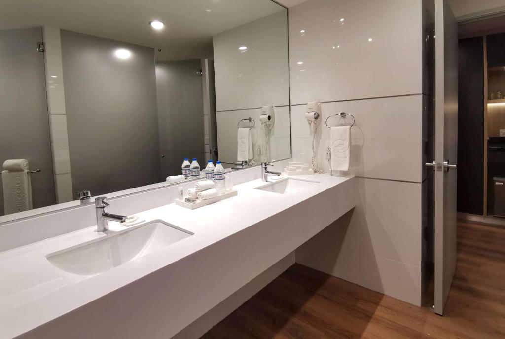 a bathroom with two sinks and a large mirror at Ramada Encore by Wyndham Guadalajara Aeropuerto in Guadalajara