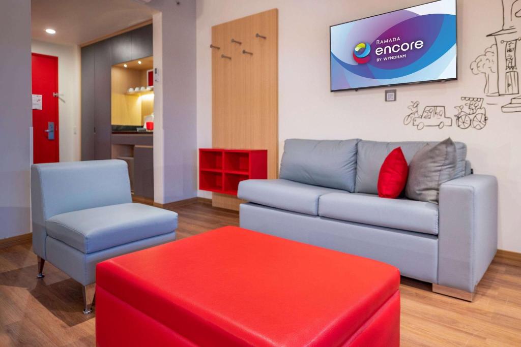 a living room with a couch and a red stool at Ramada Encore by Wyndham Guadalajara Aeropuerto in Guadalajara