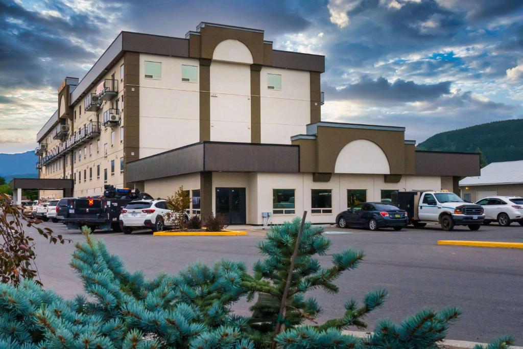 un gran edificio con coches estacionados en un estacionamiento en Quality Inn Sunshine Suites en Terrace