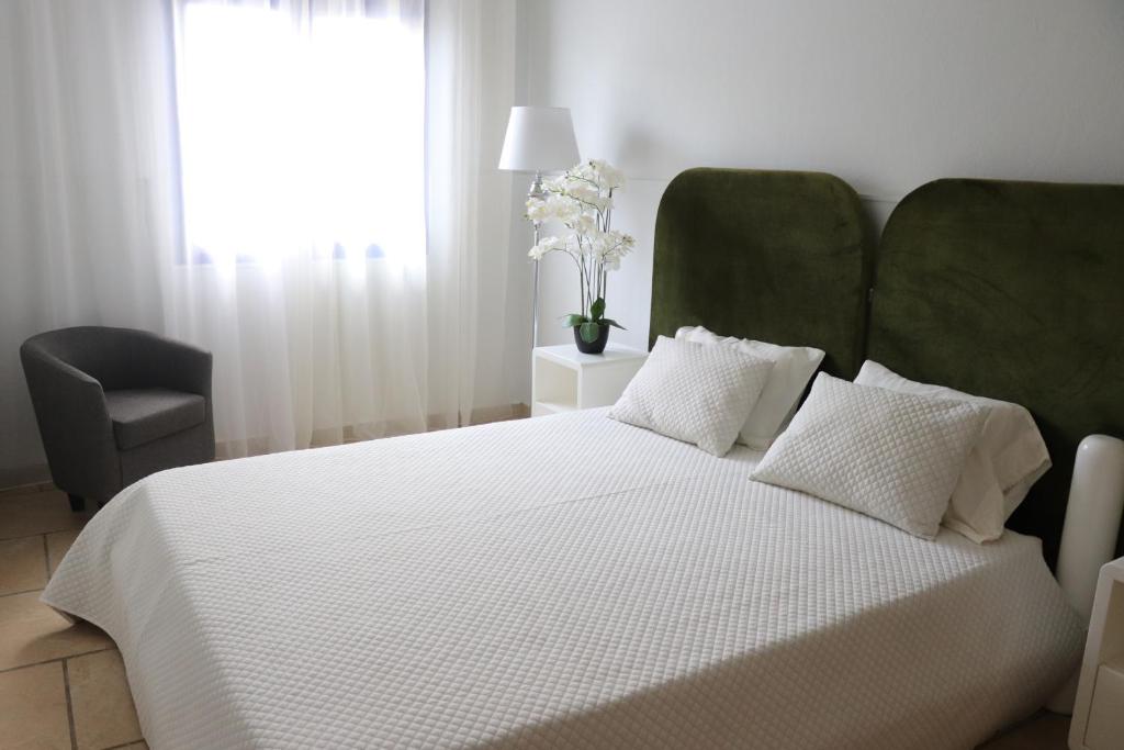 ein Schlafzimmer mit einem weißen Bett mit einem grünen Kopfteil in der Unterkunft Apartamento Moradias Djadsal próximo à Praia de Santa Maria in Espargos