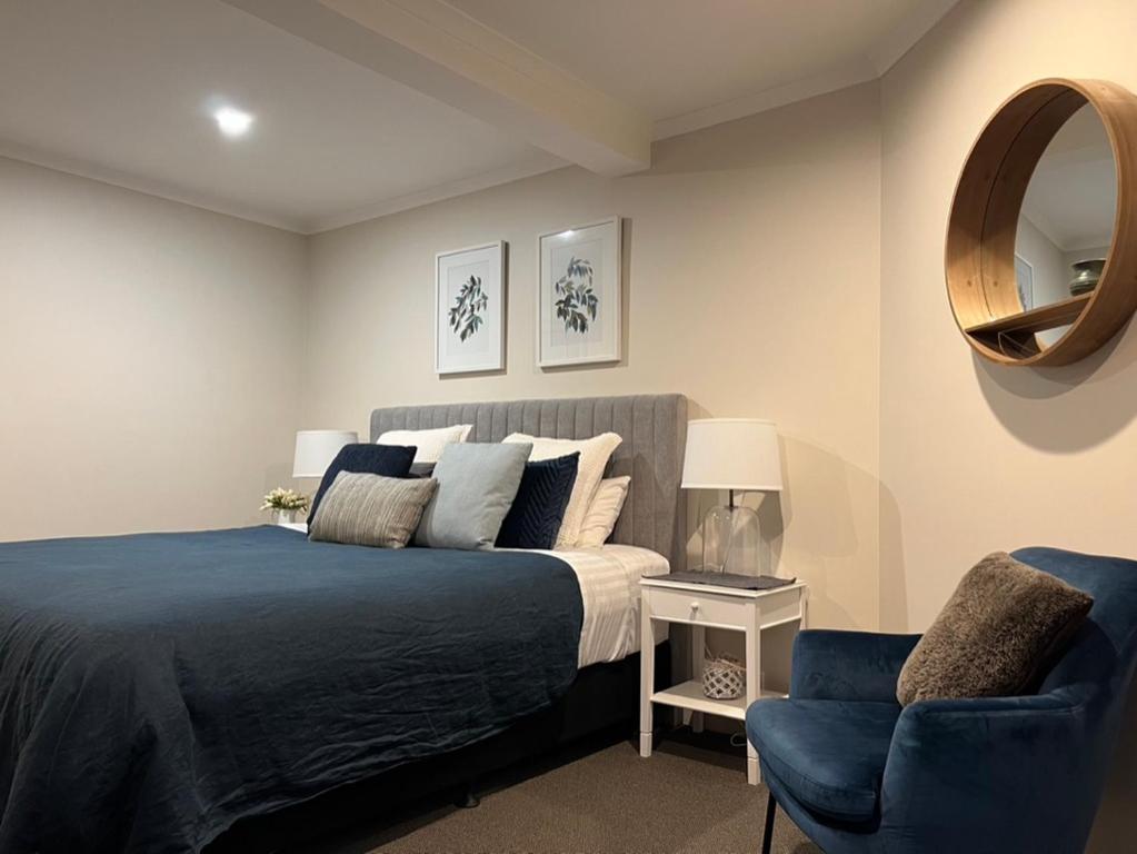 1 dormitorio con cama, silla y espejo en Westwood Lodge, en Bright