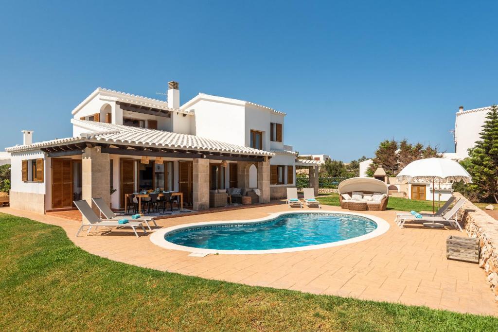 a villa with a swimming pool in front of a house at Lasaienea 4 bedroom villa, Cala Morell in Cala Morell