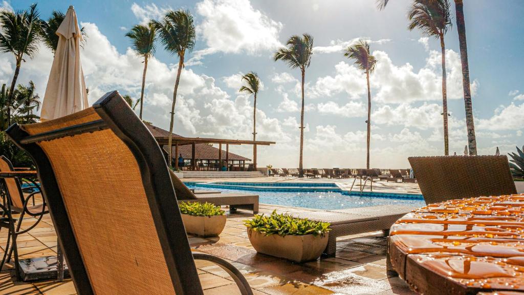 a pool with palm trees and chairs and a swimming pool at Saint Tropez Praia Hotel in Arraial d'Ajuda