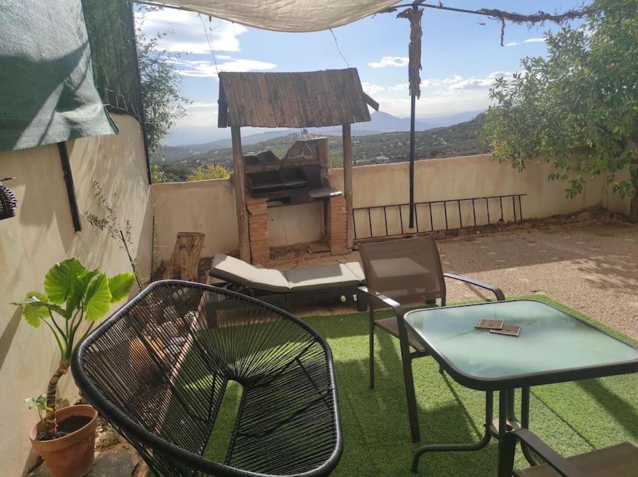 un patio con tavolo, sedie e griglia di Rustic mountain view apartment a Cogollos De La Vega