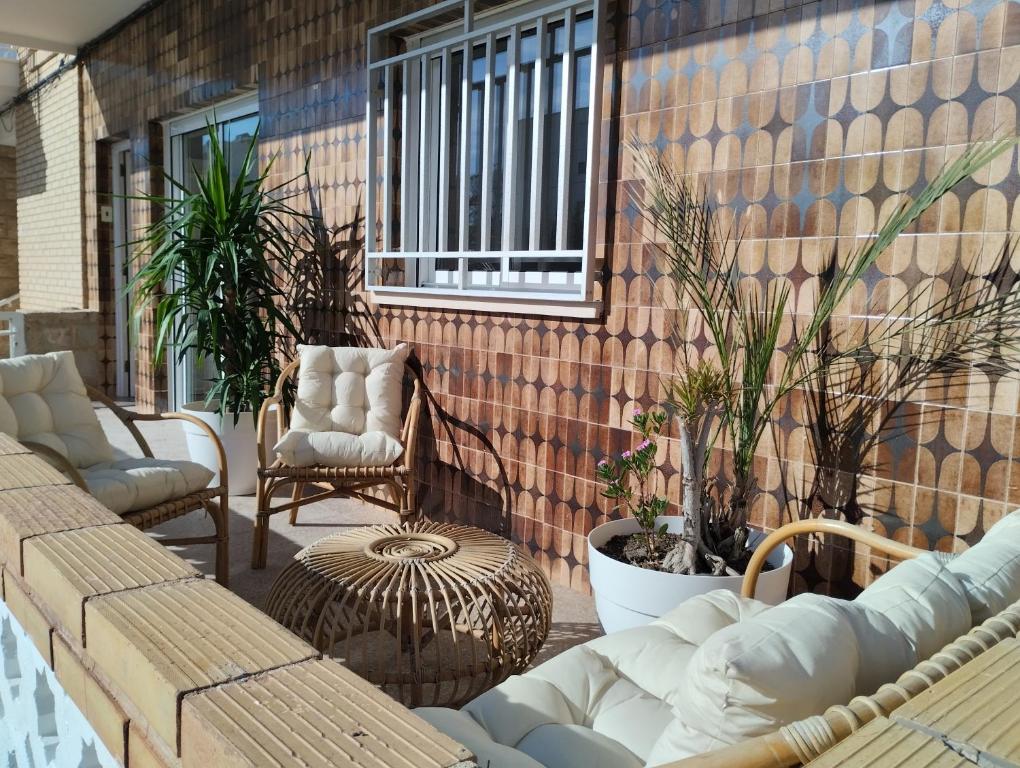 eine Terrasse mit Sofas, Stühlen und Pflanzen in der Unterkunft Piles Playa Beach Apartment in Piles