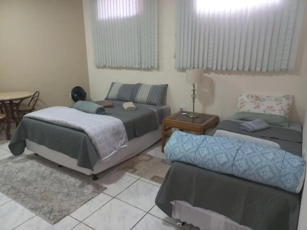 um quarto com 2 camas, um sofá e uma mesa em Loft Jardim Botânico 2 em Curitiba