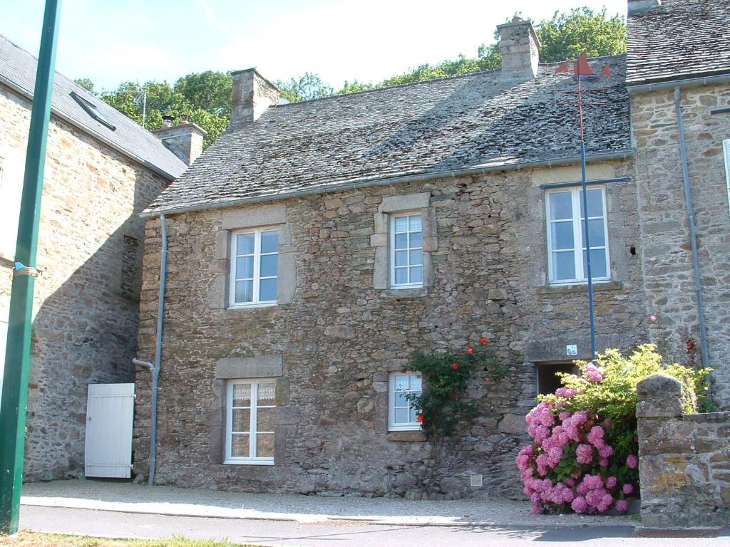 une ancienne maison en pierre avec des fleurs devant elle dans l'établissement reve capel, à Urville-Nacqueville