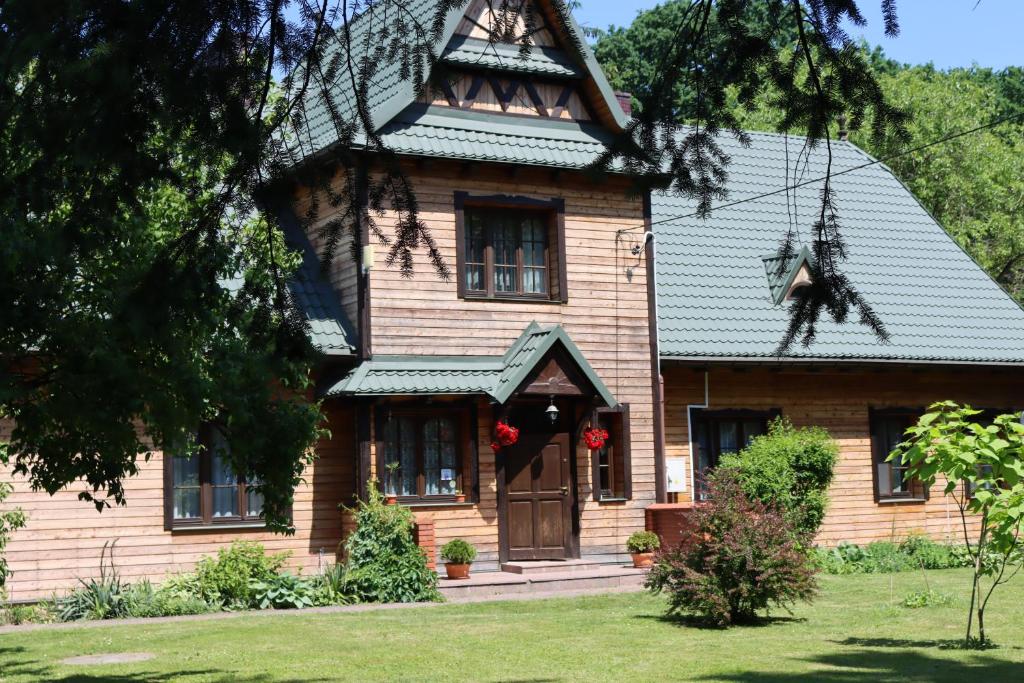 a wooden house with a gambrel roof at Kwatera Myśliwska, Nadleśnictwo Radzyń Podlaski in Wohyń