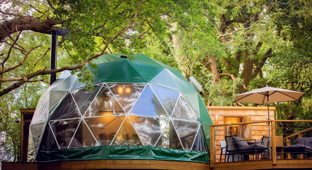 a tent with chairs and an umbrella on a deck at Luna Domes in Chiddingstone