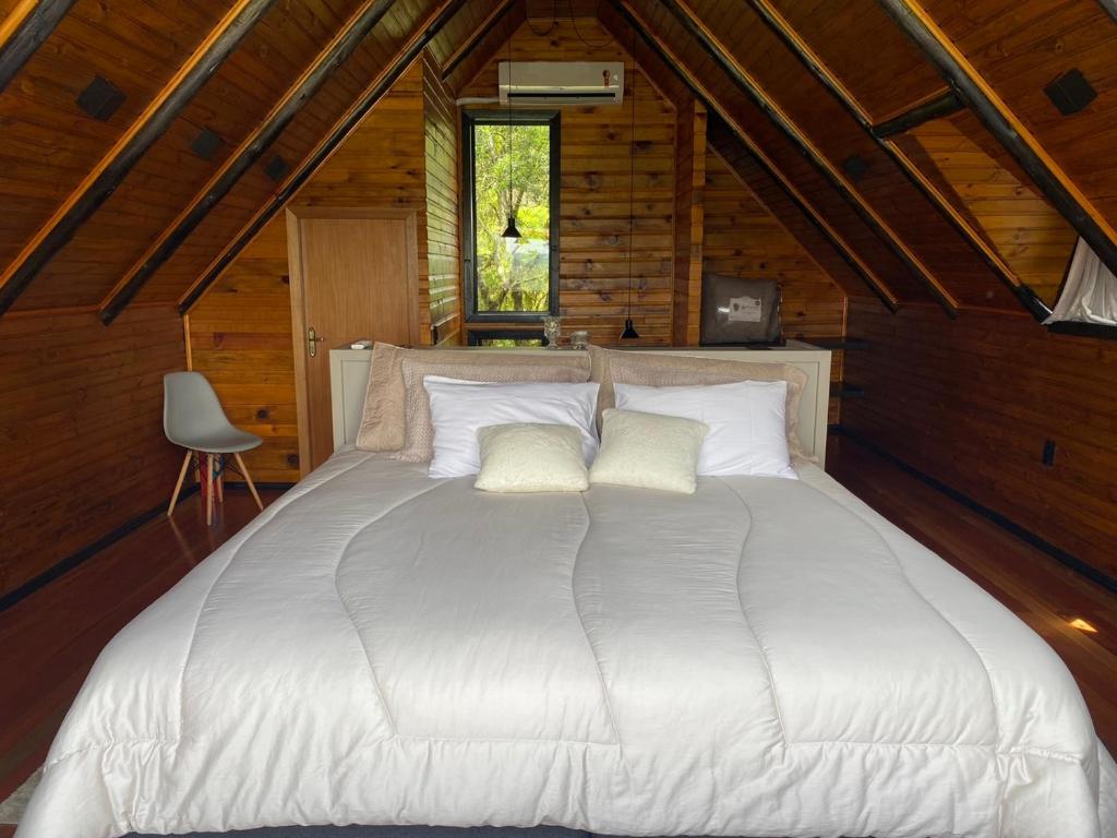 1 cama blanca grande en una habitación con techo de madera en Morada Alto Das Nuvens en São José dos Ausentes