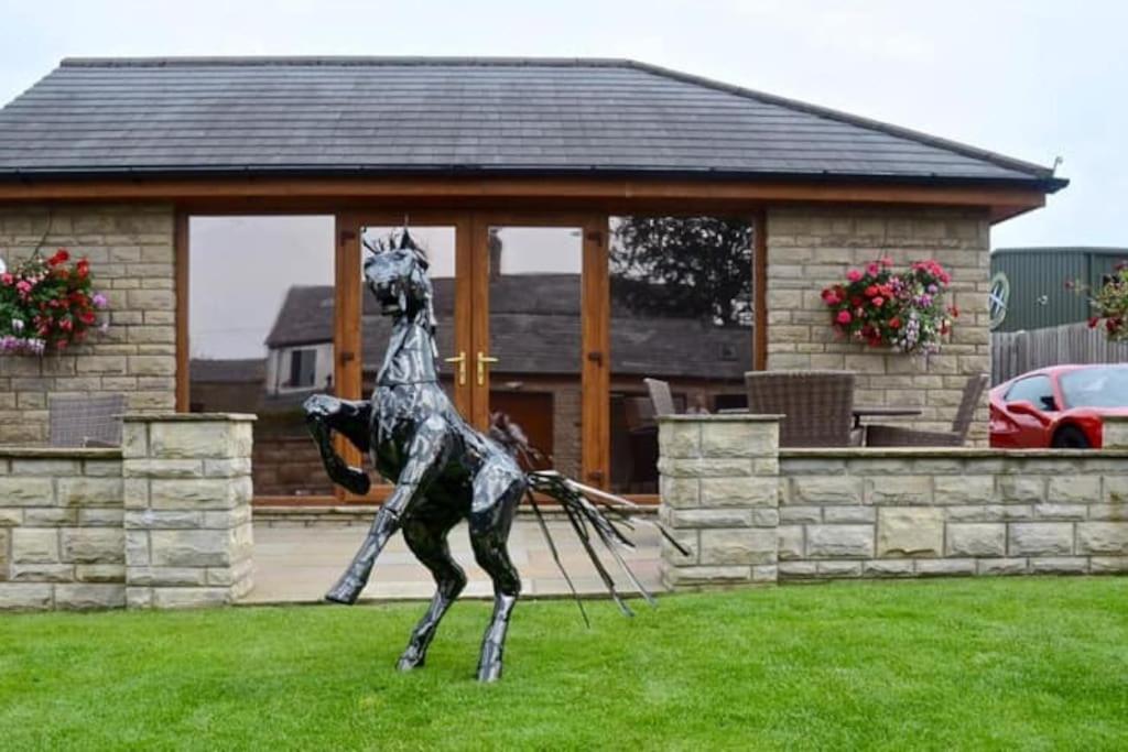 une statue d'un cheval dans l'herbe devant une maison dans l'établissement Prancing Horse Cottage, à Sabden