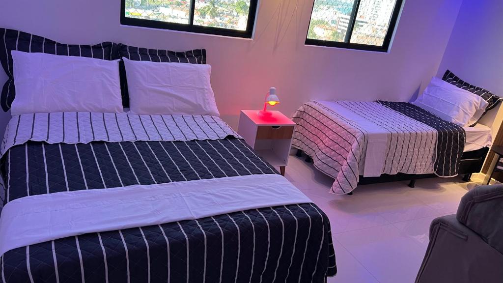 ein Schlafzimmer mit 2 Betten und einem Tisch mit einer Lampe in der Unterkunft AP studio805 in Maceió