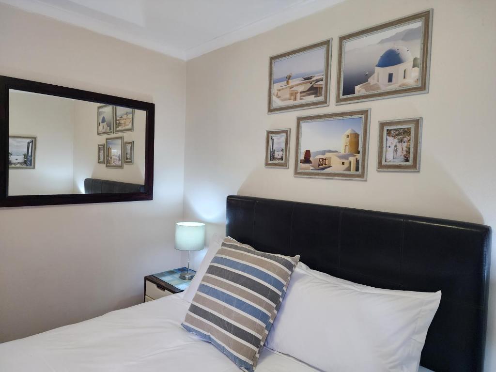 a bedroom with a bed with a black headboard and a mirror at Little Greece in Cape Town