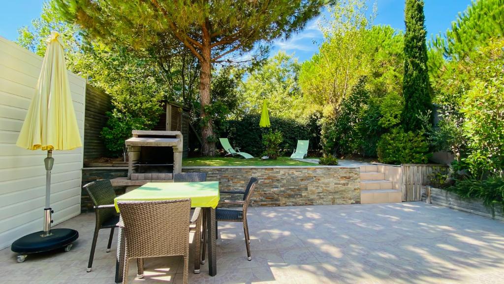 une terrasse avec une table, des chaises et un parasol dans l'établissement Charmante villa à proximité de la plage du Petit Sergent, au Bois-Plage-en-Ré