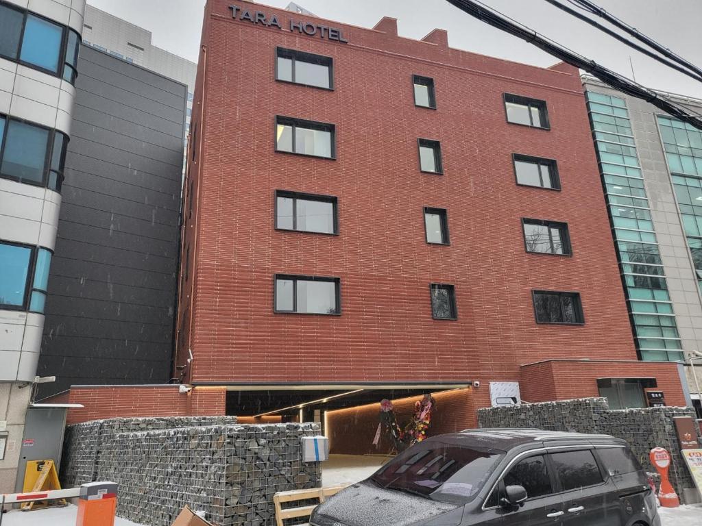 a car parked in front of a red brick building at Hotel TARA in Seoul