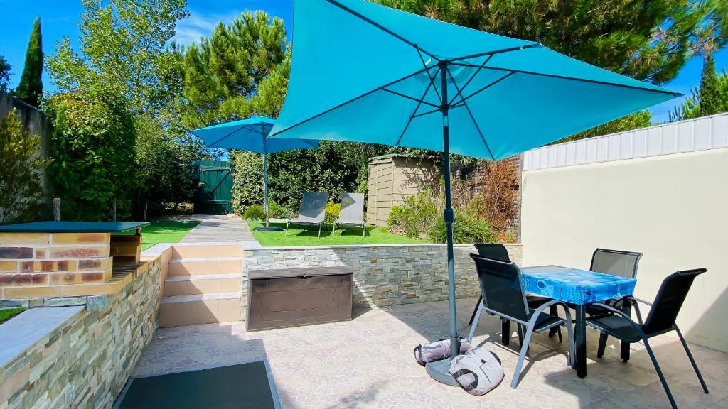 einen Tisch mit einem blauen Regenschirm auf einer Terrasse in der Unterkunft Villa récente avec accès à la plage par chemin à l'arrière de la maison in Le Bois-Plage-en-Ré