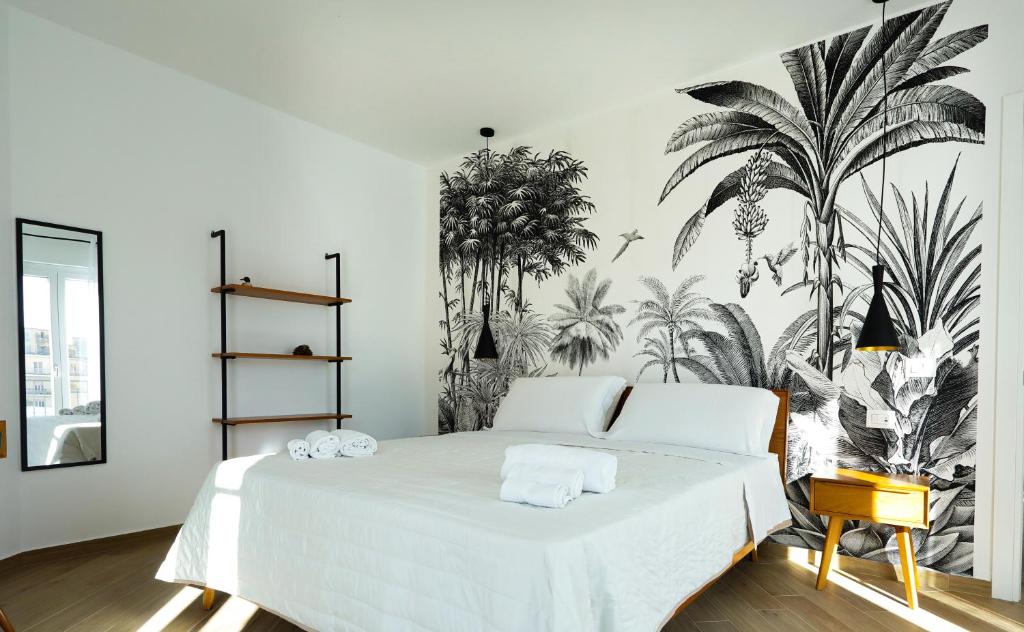 a bedroom with a large white bed with plants on the wall at Il Canto di Ligea in Lamezia Terme