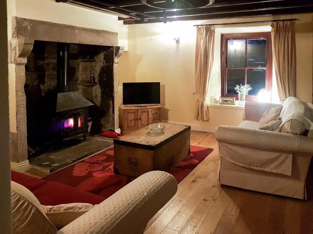 a living room with a couch and a fireplace at Syke Cottage in Mickleton