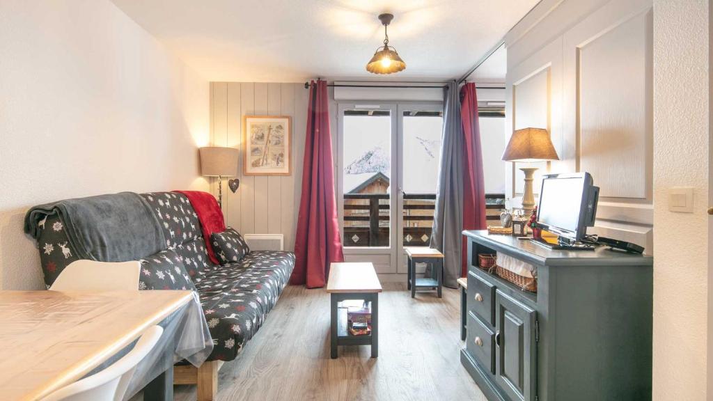 ein Wohnzimmer mit einem Sofa und einem TV in der Unterkunft Les Tetras - 63 - Studio moderne - 4 pers in Saint-Sorlin-dʼArves