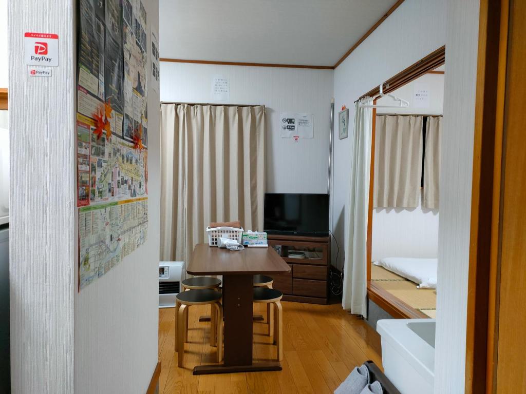 een kleine kamer met een tafel en een bed bij Guesthouse Maple Nikko in Nikko