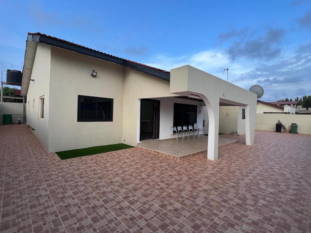 Cette grande maison blanche dispose d'une terrasse en briques. dans l'établissement Inviting 3-Bed House in Accra, à Accra