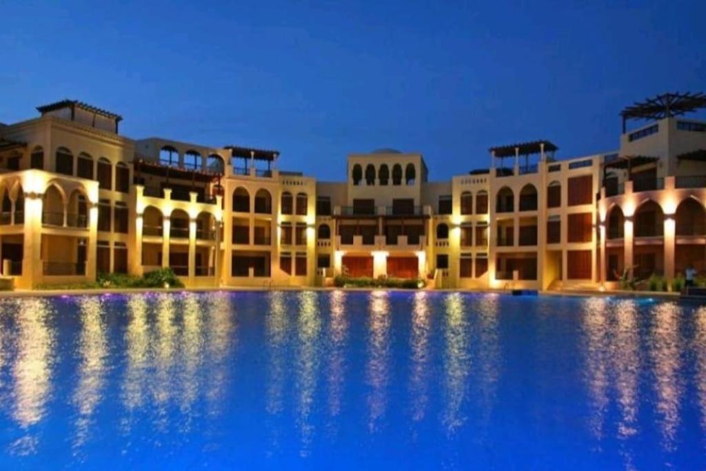 a large building with a large swimming pool at night at Sun and beach apartment in Aqaba