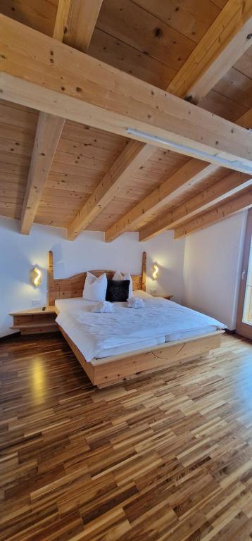 a bedroom with a large bed with wooden floors at Chasa Castello relax & spa in Samnaun