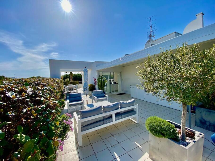 une maison avec une terrasse agrémentée de bancs et d'arbres dans l'établissement Le Swing N01 toit terrasse, à La Grande Motte