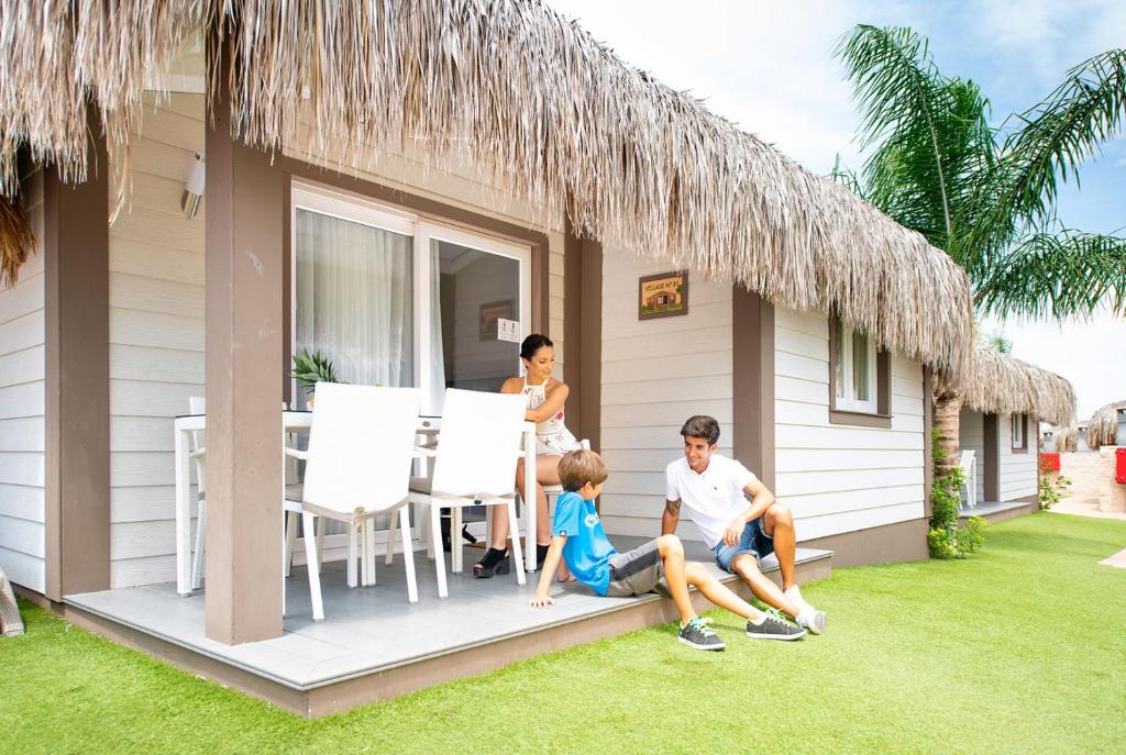 a family sitting on the porch of a house at La Marina Resort in La Marina