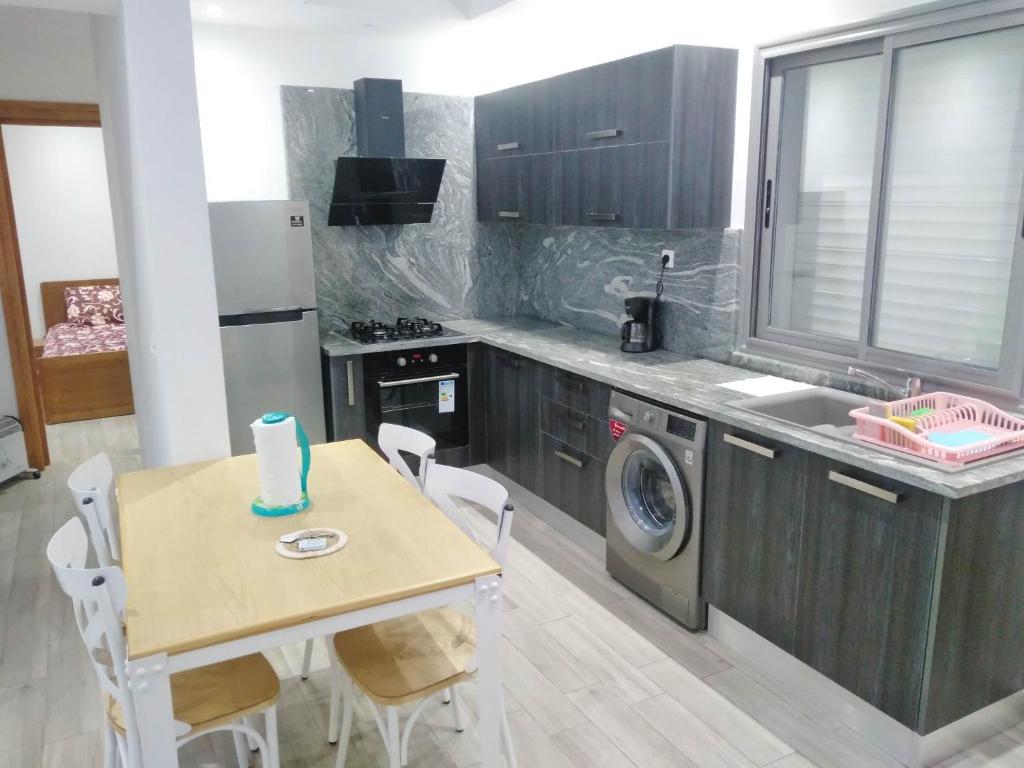 a kitchen with a table and a washing machine at Residence Inès djerba Appartement de Lux in Houmt Souk