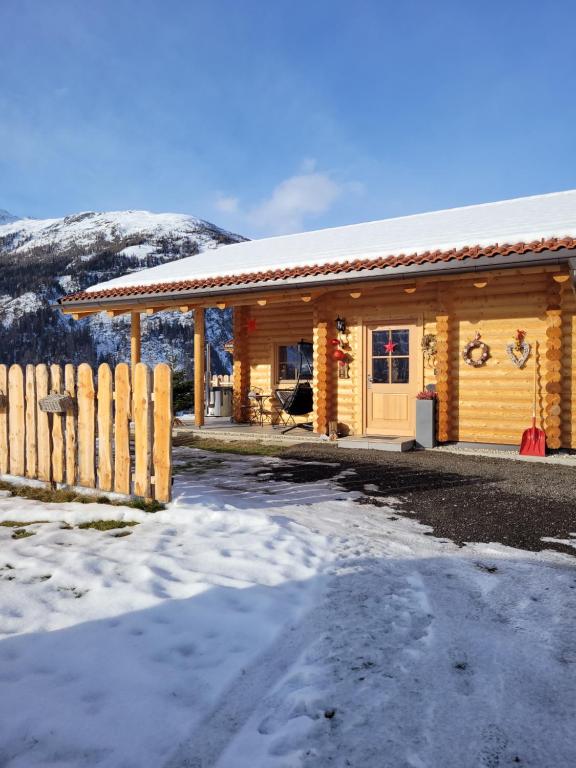Connys Naturberghütten في غروسكرتشاين: كابينة خشب فيها سياج في الثلج