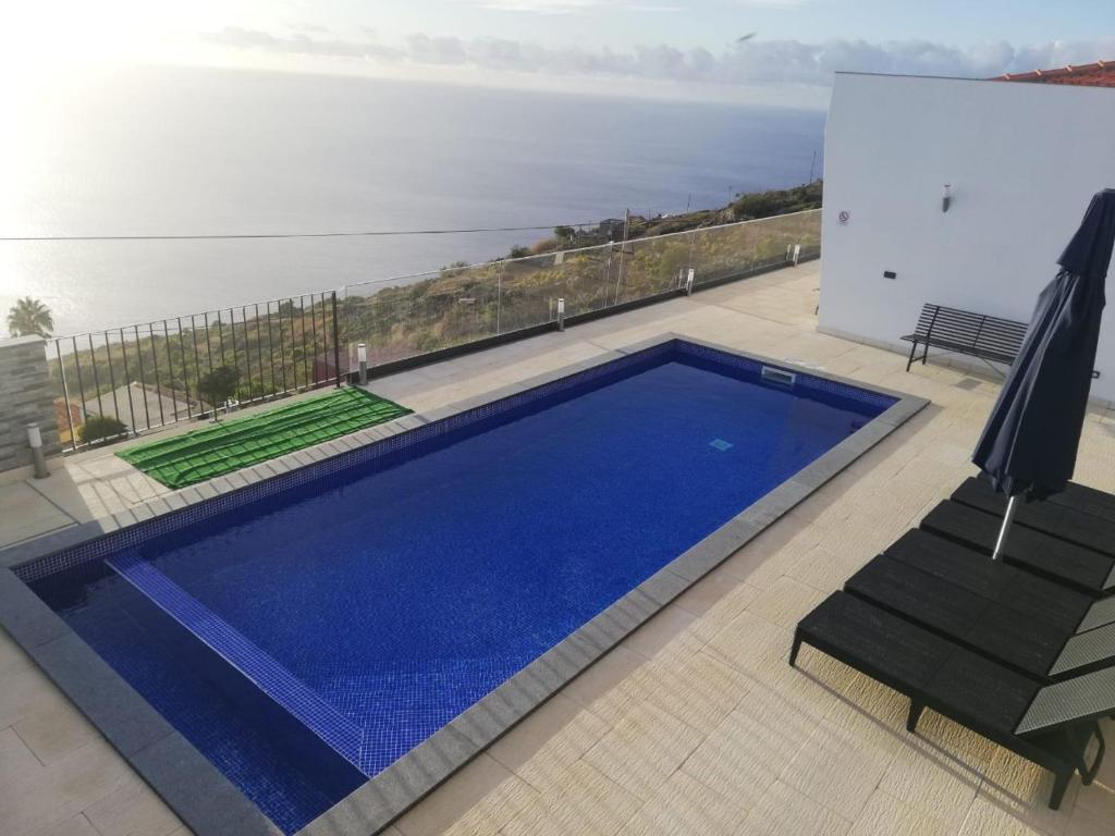 una piscina azul con vistas al océano en Majestic Seaview Villa, en Fajã da Ovelha