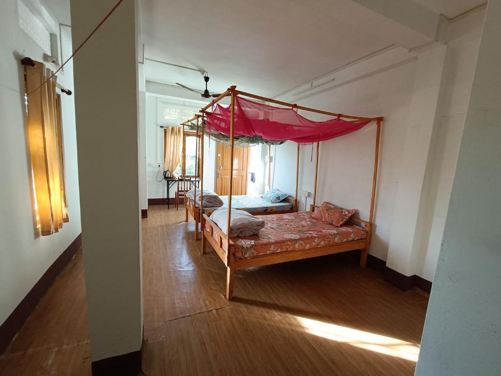 a bedroom with a four poster bed with a canopy at Manipur House in Imphal